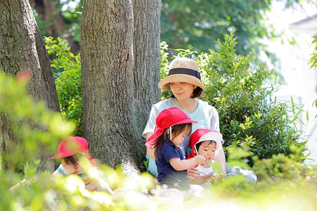 写真:木陰で休む保育士と園児